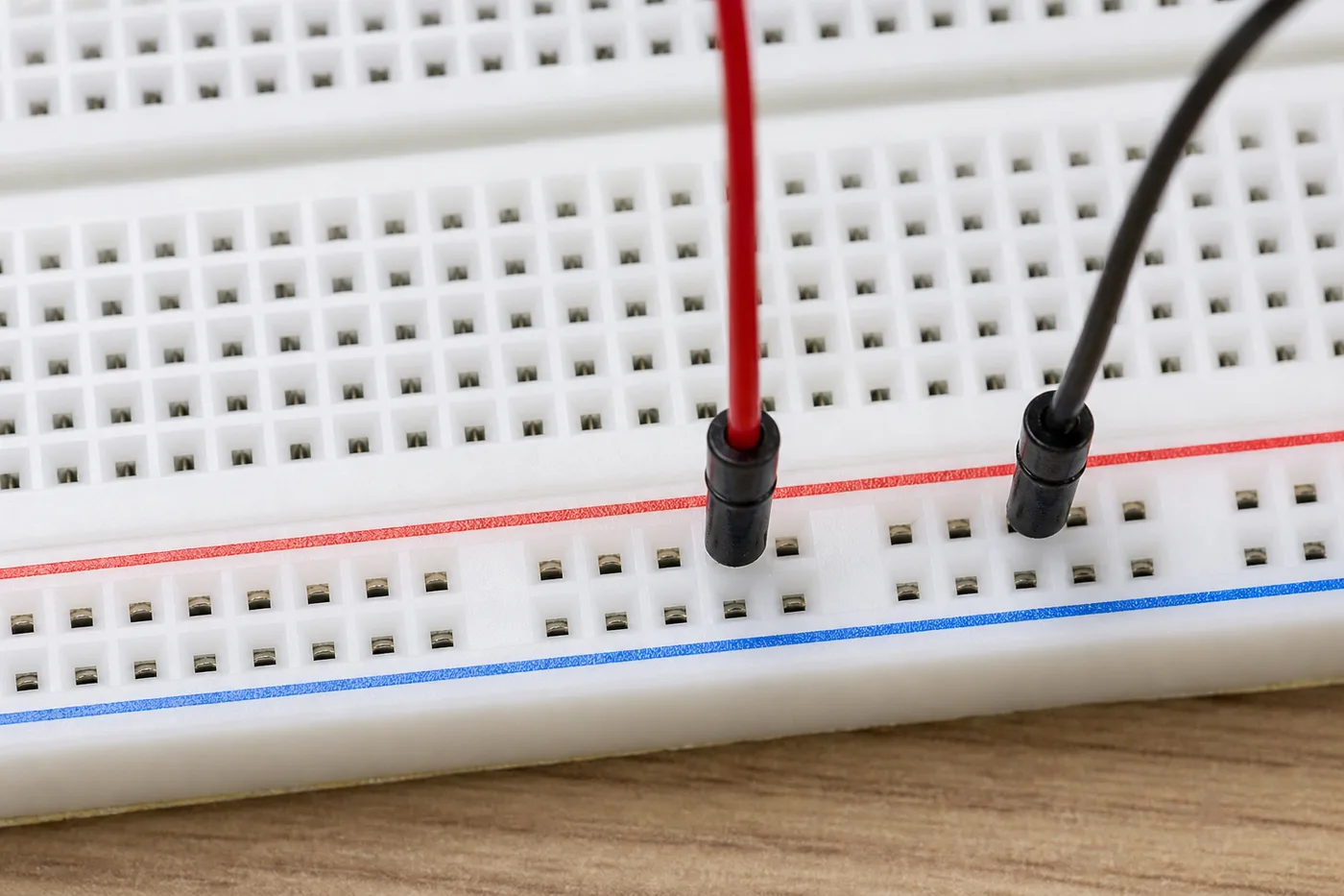 Horizontal power rails on a breadboard with red and blue jumper wires Horizontal power rails on a breadboard with red and blue jumper wires